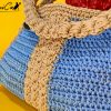 L'immagine mostra una borsa azzurra all'uncinetto con strisce verticali gialle, dotata di un manico coordinato e una chiusura magnetica. Sogno Mediterraneo: il fascino del mare nella tua mano.